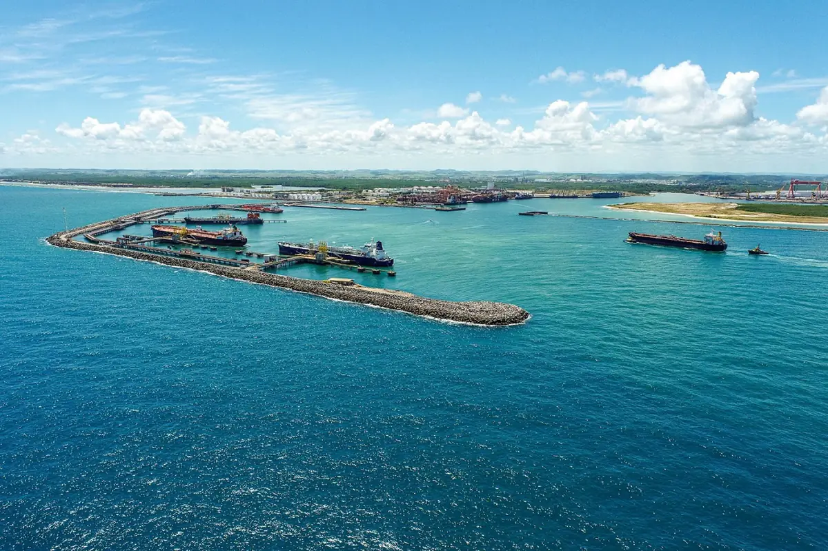 Aerial view of the Port of Suape: tankers alongside the liquid bulk piers behind the breakwater, a ship with a tug in the access channel and the inner port beyond.