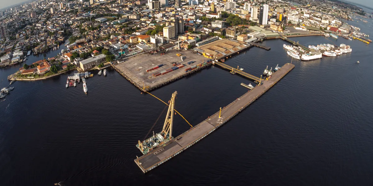 Aerial view of the public Port of Manaus on the Rio Negro, with its floating pier, container yard and passenger vessels along the downtown waterfront.